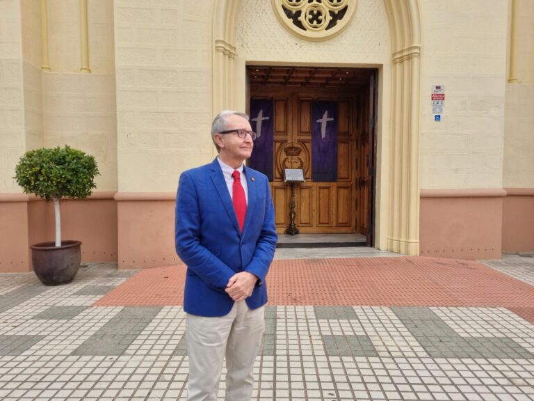 Hombre de pie frente a una iglesia con puertas de madera.