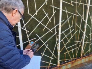 Hombre usando un teléfono móvil frente a una pared con diseño artístico.