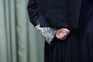 Mano de un juez con toga y encaje en la muñeca