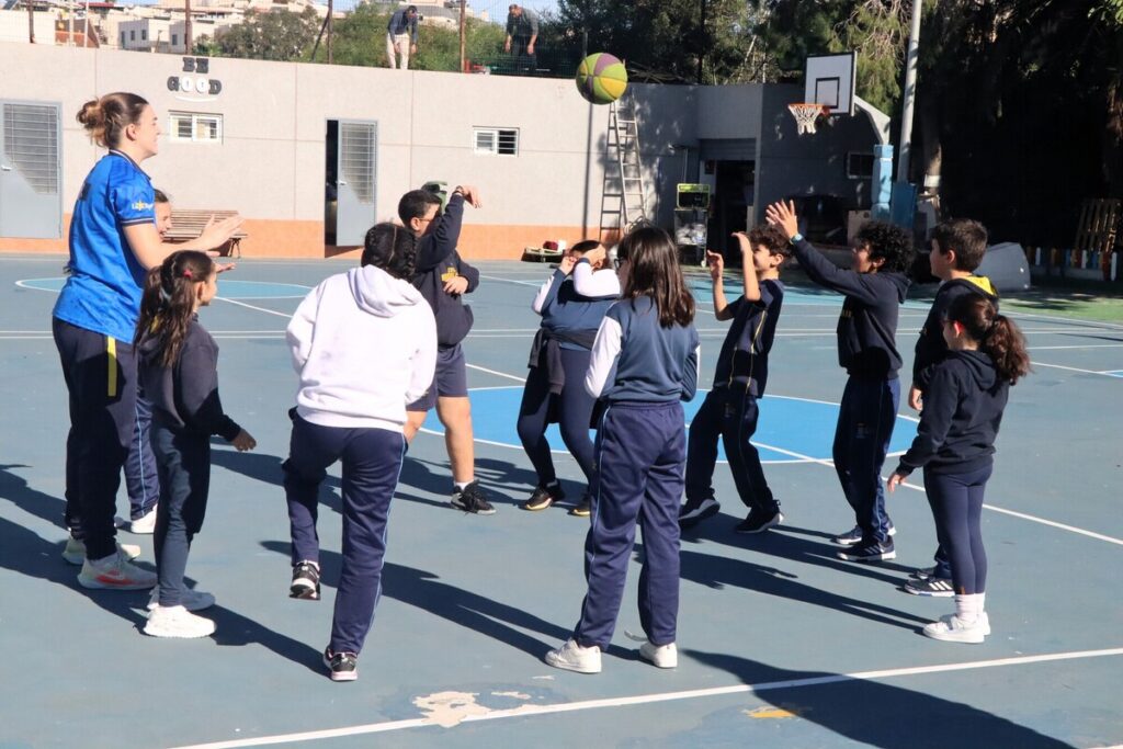 Niños jugando baloncesto en un campo deportivo al aire libre