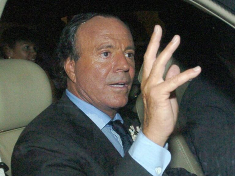 Julio Iglesias en un coche, levantando la mano en señal de respuesta.