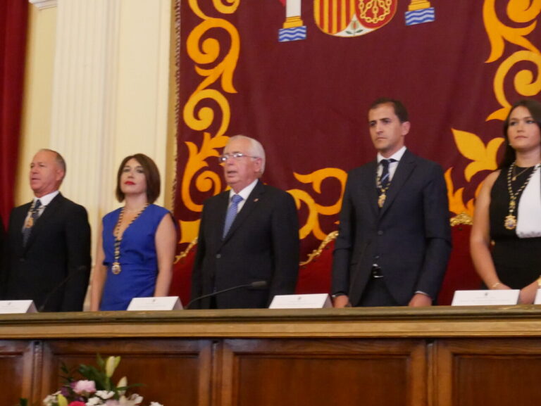 Personas en un evento formal en Melilla con banderas de España