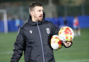 Entrenador sosteniendo balones en un campo de fútbol