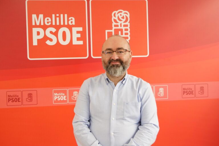 Representante del PSOE en Melilla posando frente a un fondo rojo