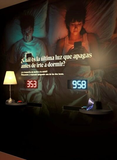 Pareja en la cama usando dispositivos electrónicos antes de dormir