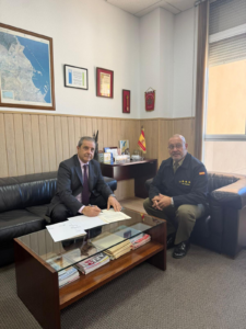 Dos hombres sentados en una oficina firmando un documento.