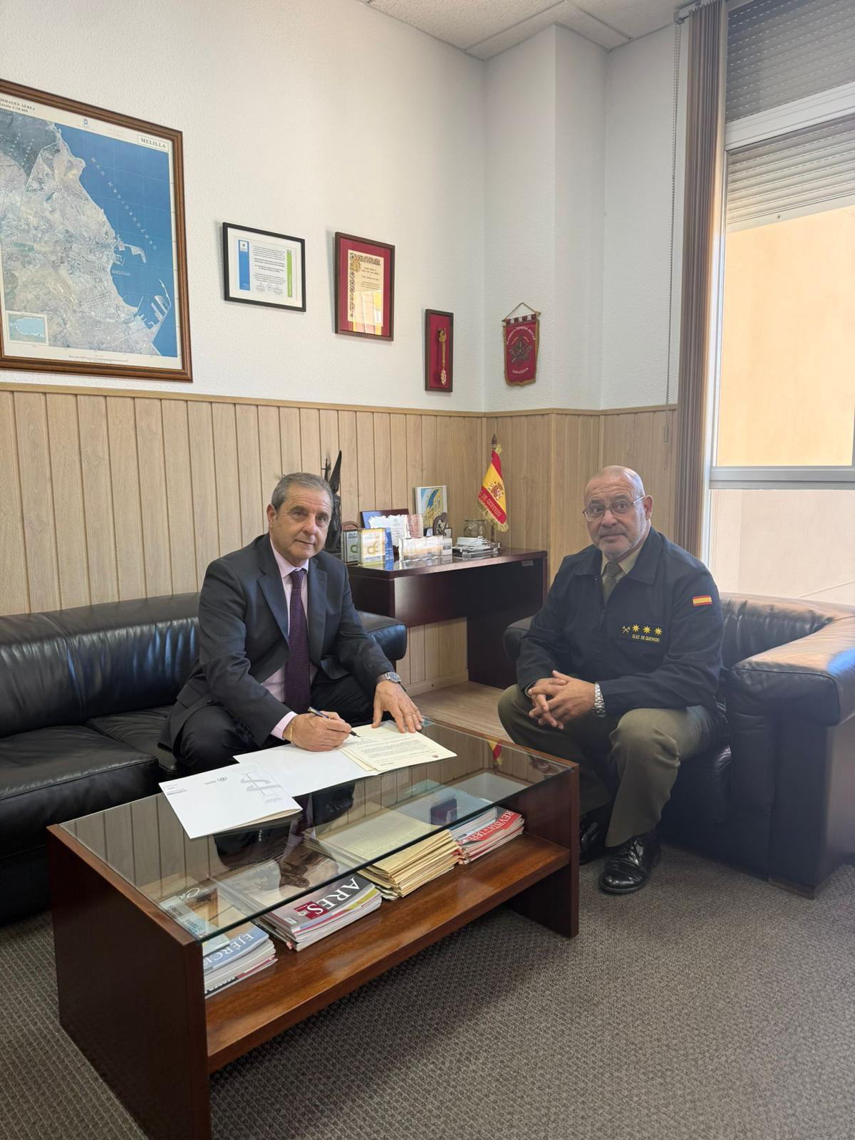 Dos hombres sentados en una oficina firmando un documento.
