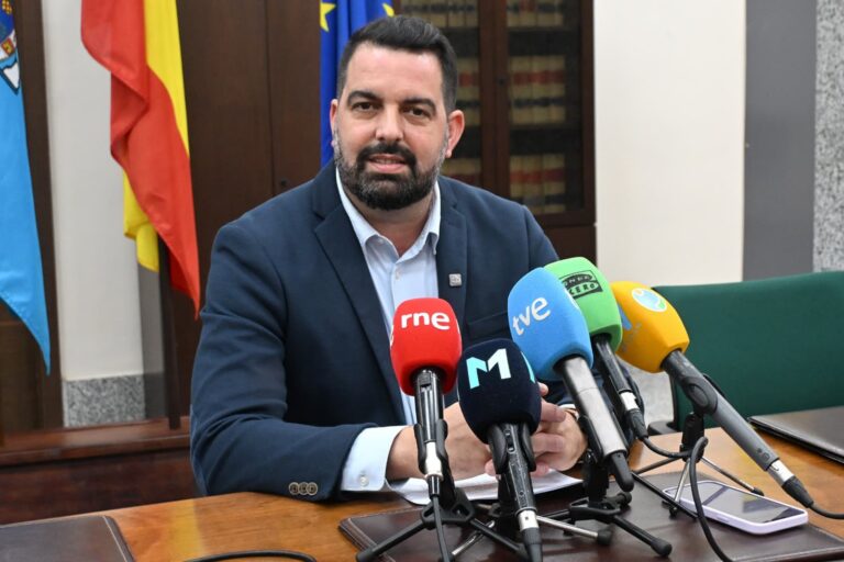 Hombre en rueda de prensa con micrófonos de diferentes medios