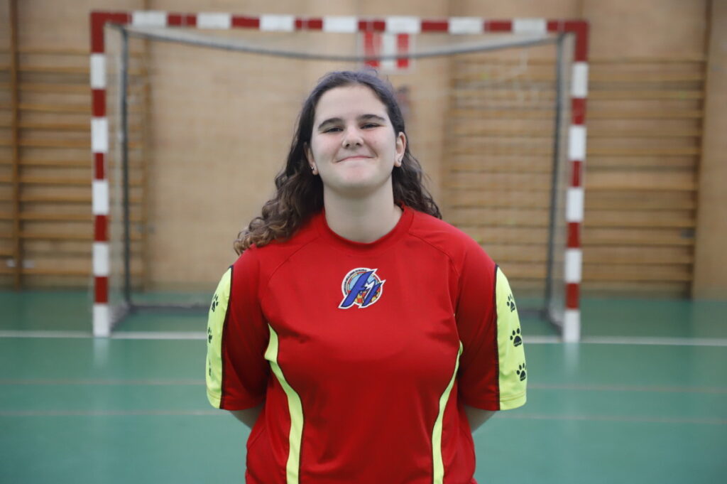 Jugadora de fútbol sala femenino en camiseta roja sonriendo en un pabellón