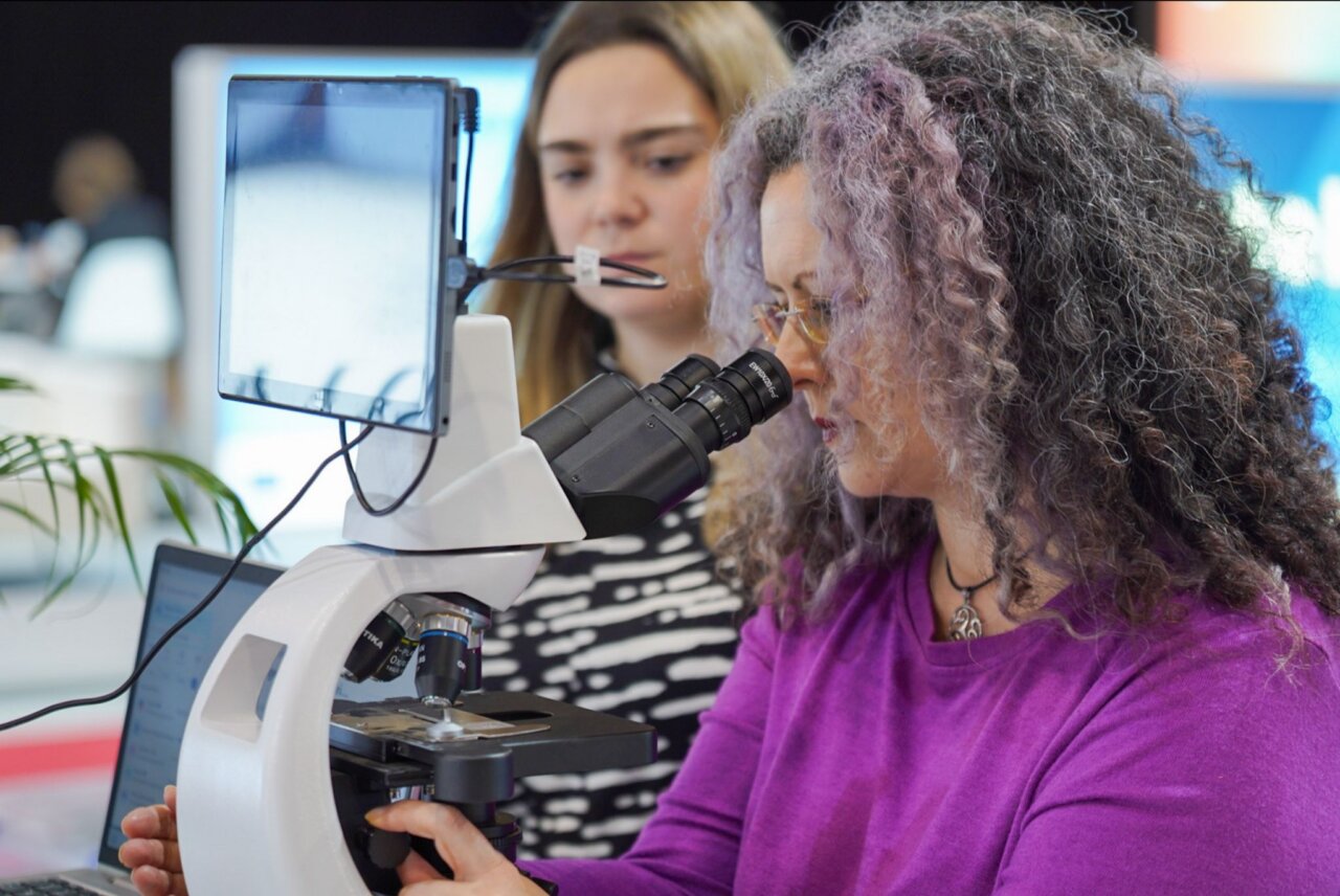 Mujer observando a través de un microscopio en feria de ciencia