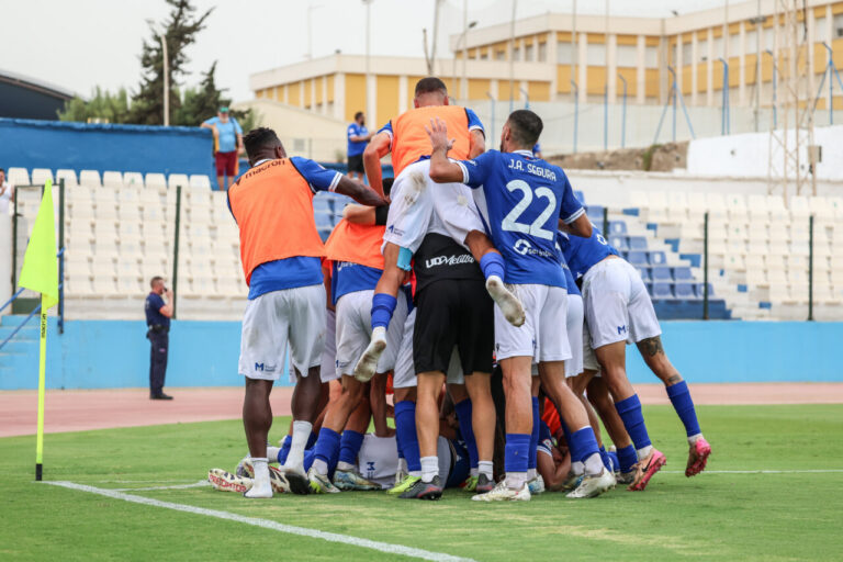 Jugadores de la U.D. Melilla celebrando un momento en el campo.