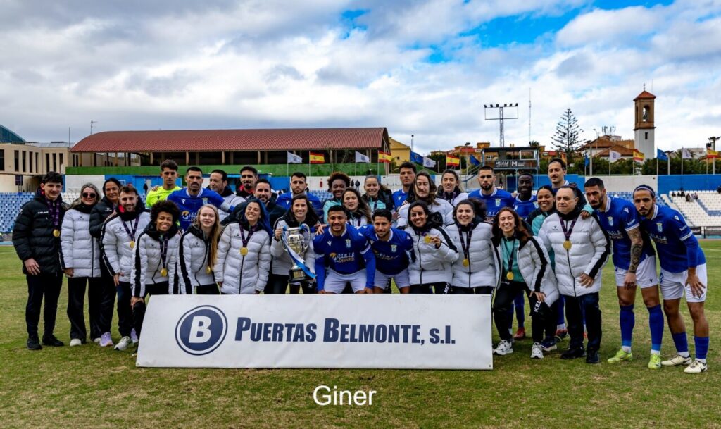 Jugadores y cuerpo técnico de la U.D. Melilla celebrando una victoria en el estadio.