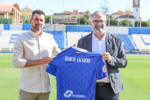 Rafael Ocaña mostrando una camiseta de la U.D. Melilla en el campo