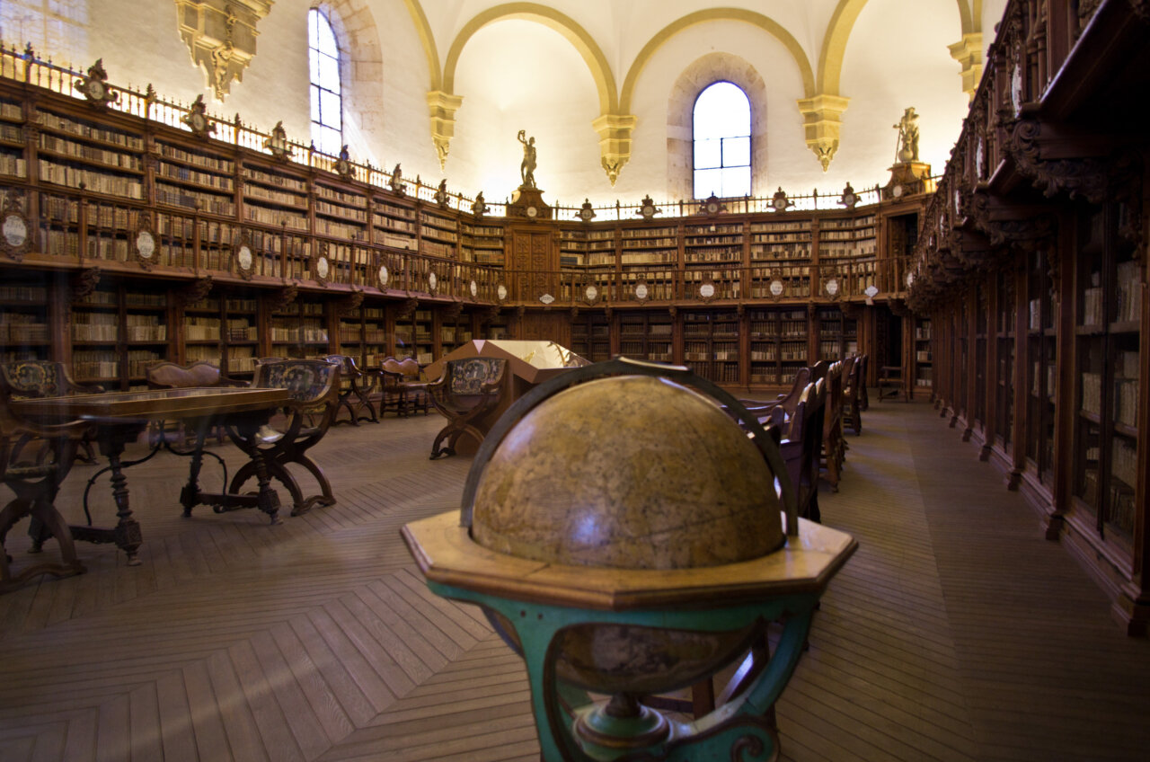 Interior de la biblioteca histórica de la Universidad de Salamanca con estanterías de libros.