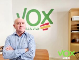 Persona en oficina con logo de VOX Melilla al fondo