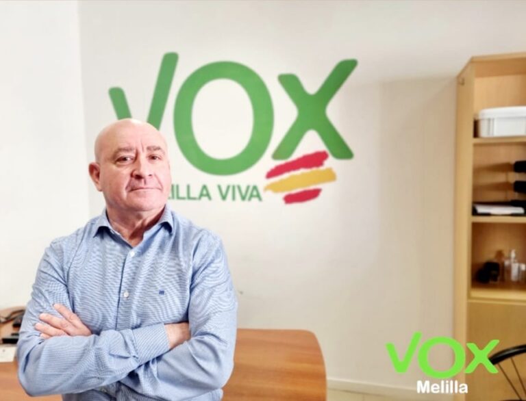 Persona en oficina con logo de VOX Melilla al fondo