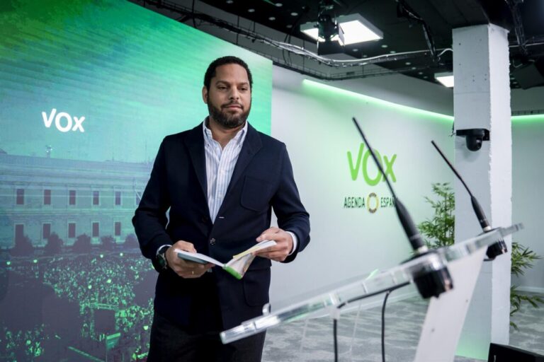 Un representante de Vox en un evento con fondo verde y logo de Vox