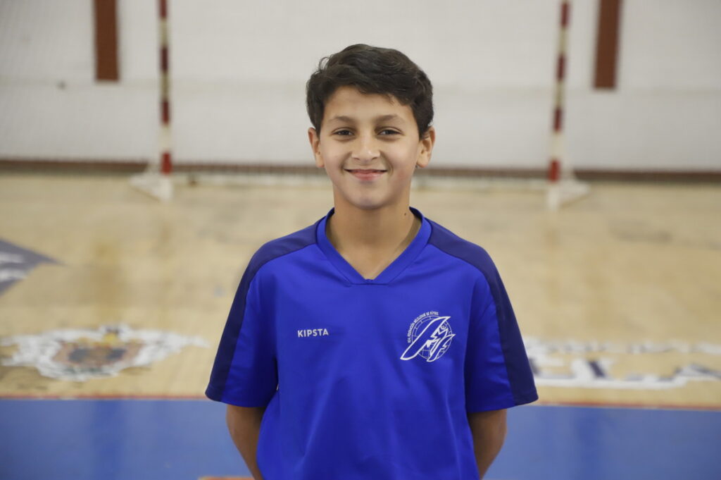 Niño sonriente con camiseta azul en un pabellón deportivo