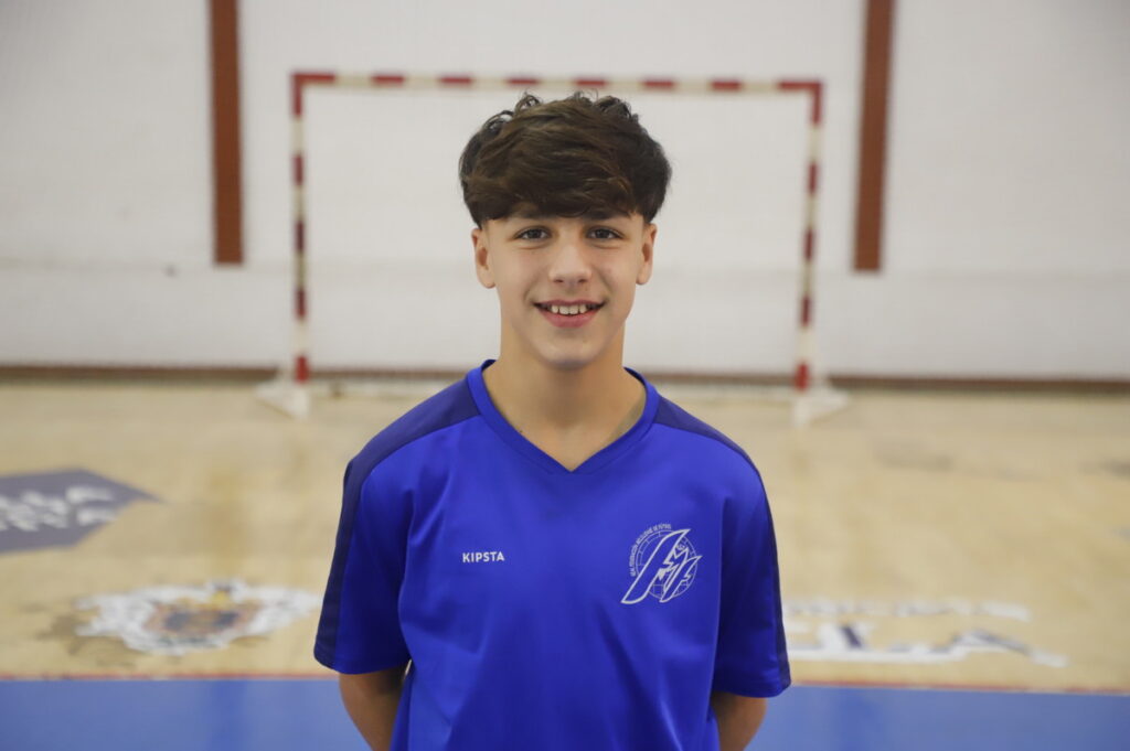 Joven jugador de fútbol sala en camiseta azul sonriente en el pabellón