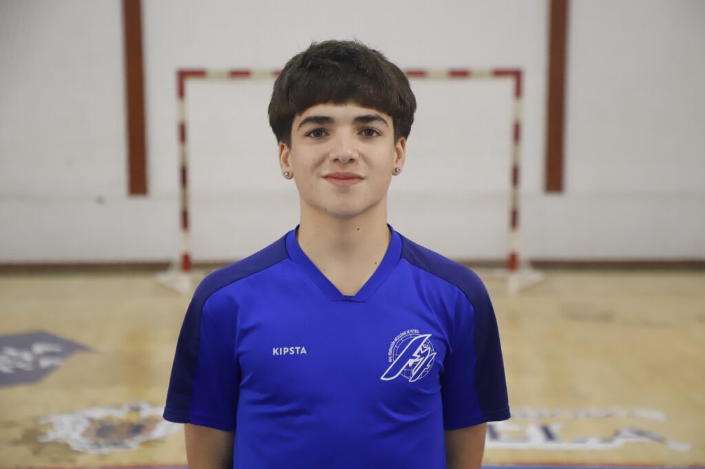 Joven jugador de fútbol sala en uniforme azul en un pabellón deportivo.