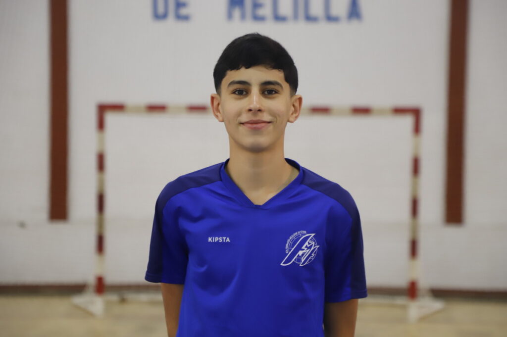 Joven jugador de fútbol sala en camiseta azul sonriendo en el pabellón