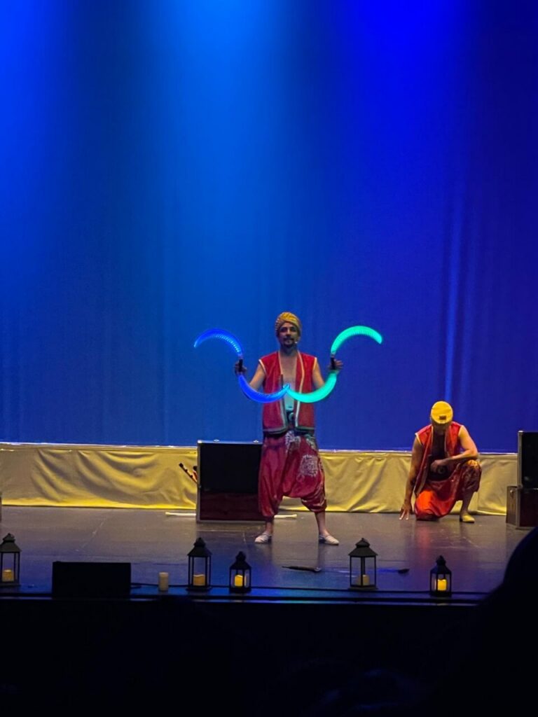 Artistas realizando malabares con luces en el escenario del teatro
