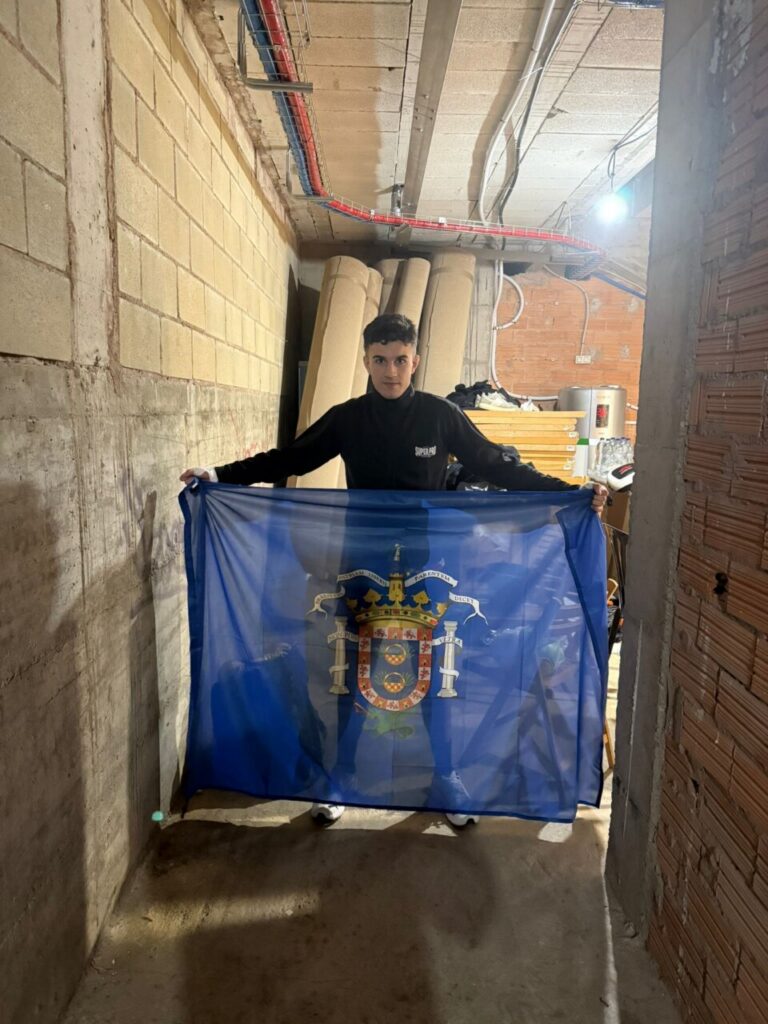 Ayman Chadghani sosteniendo una bandera en un lugar interior