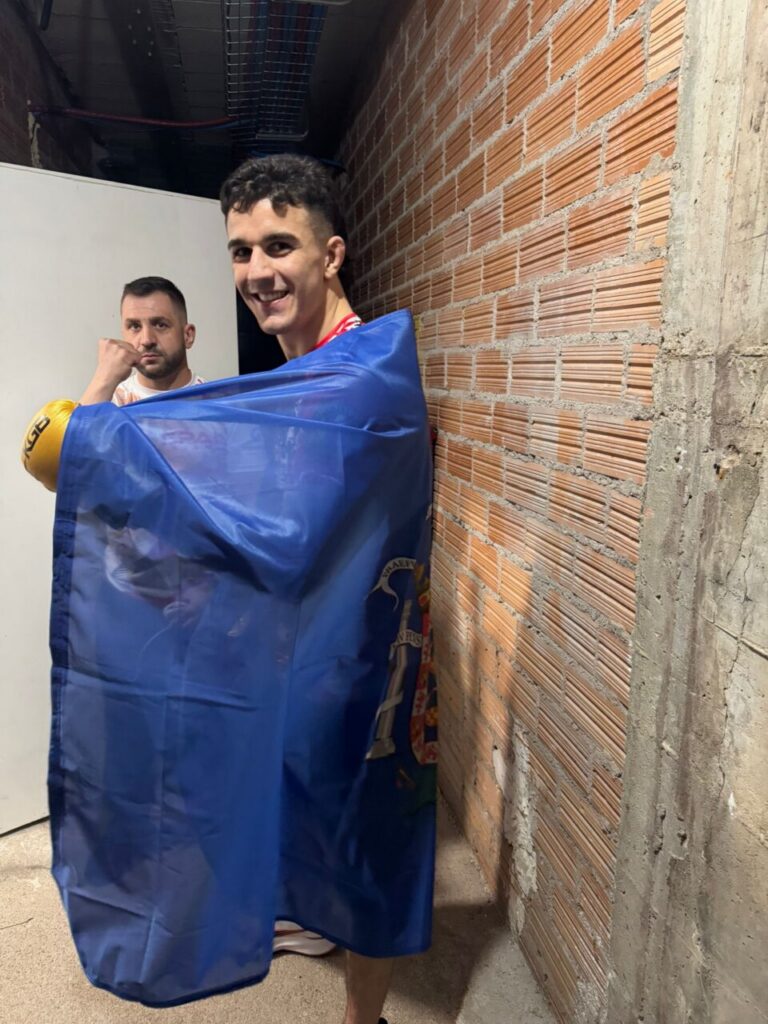 Ayman Chadghani sonriente con una bandera en el evento de MMA