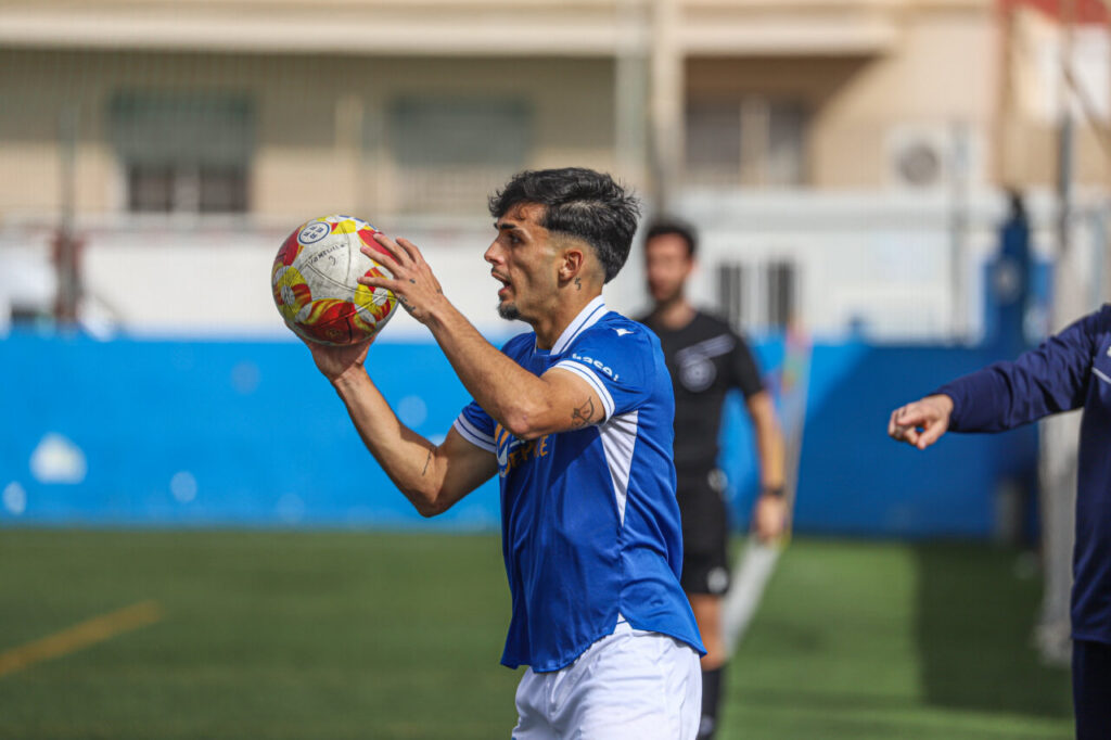 Jugador del filial de la U.D. Melilla lanzando el balón durante un partido