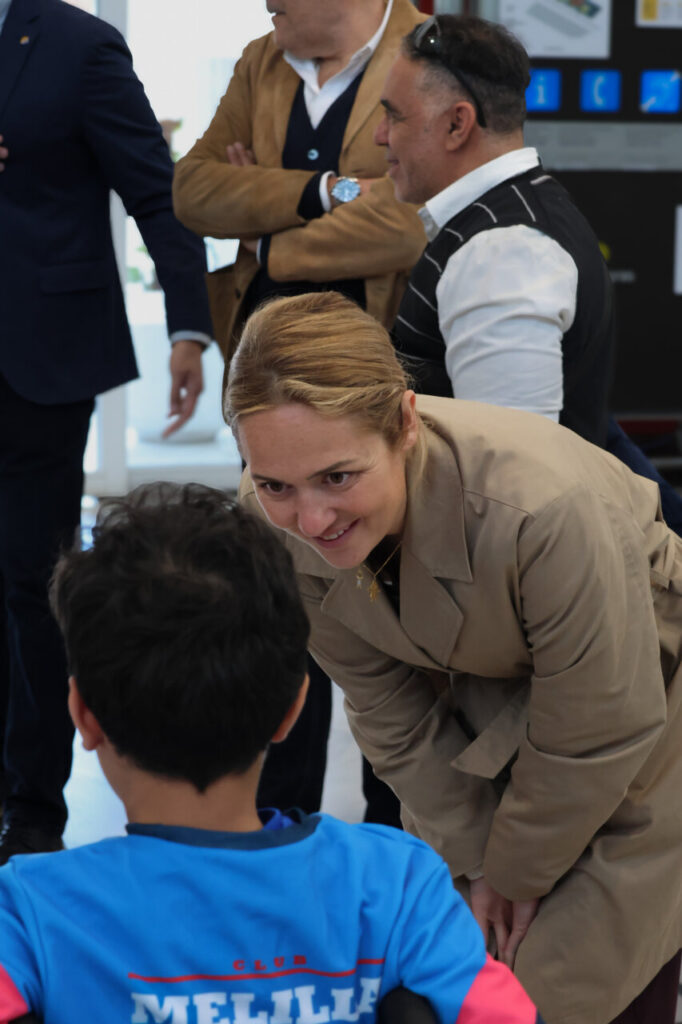 Interacción entre una mujer y un niño en silla de ruedas en un evento deportivo.