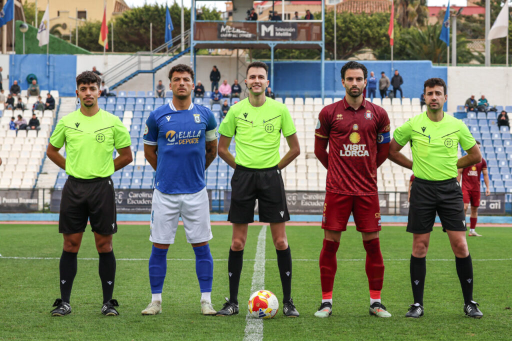 Jugadores y árbitros alineados antes del partido entre U.D. Melilla y Lorca Deportiva.