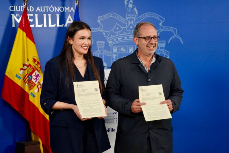 Dos personas sosteniendo documentos en un acto oficial en Melilla