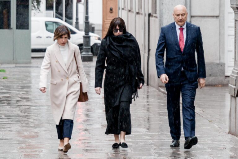 Tres personas caminando bajo la lluvia en una calle de Madrid