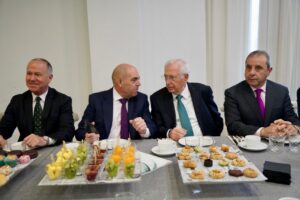 Cuatro hombres conversando en una mesa con postres y bebidas.