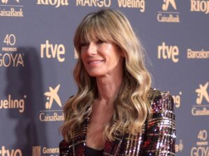 Begoña Gómez sonriendo en un evento con fondo decorado