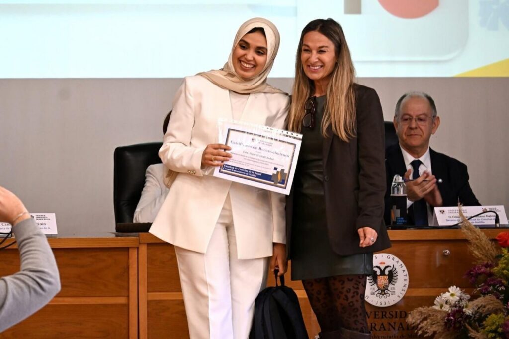 Dos mujeres sonrientes sosteniendo un certificado en un evento universitario