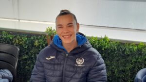 Persona sonriendo con chaqueta deportiva en un entorno verde