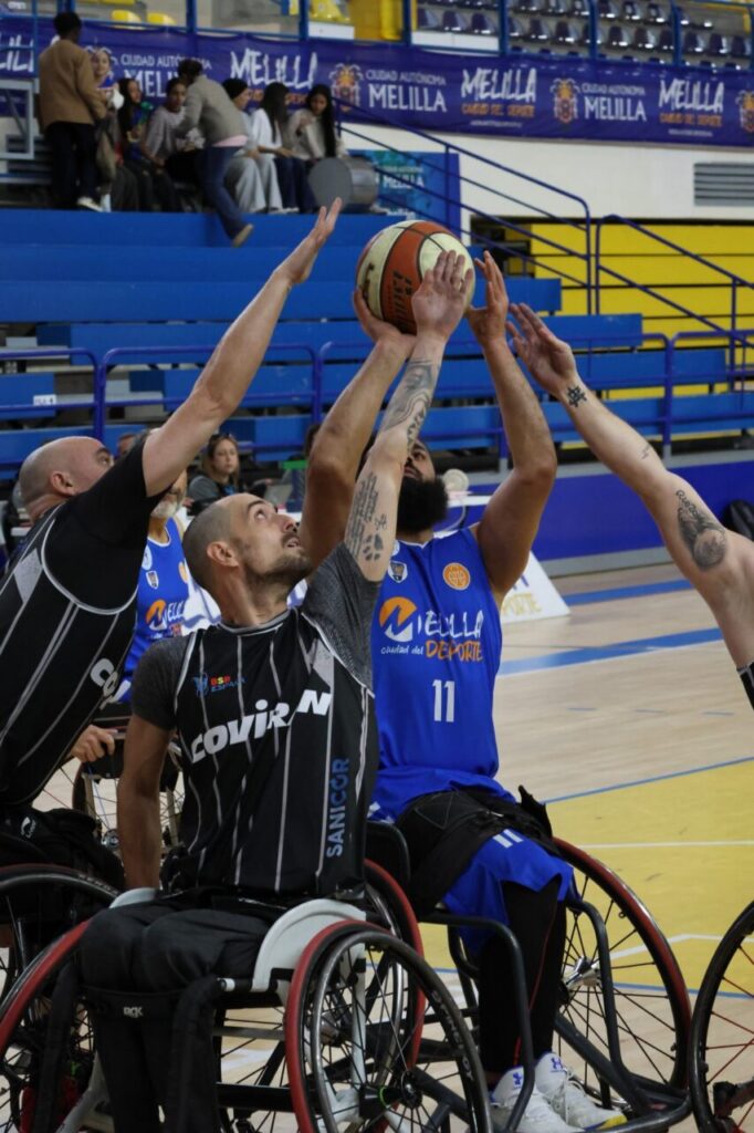 Jugadores de baloncesto en silla de ruedas compiten por el balón en un partido.