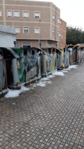 Contenedores quemados tras incendios en Melilla, con espuma en el suelo.