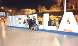 Grupo de jóvenes extutelados en Melilla junto al letrero de la ciudad.