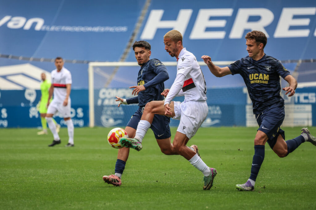 Jugadores de U.D. Melilla y UCAM Murcia en un partido de fútbol.