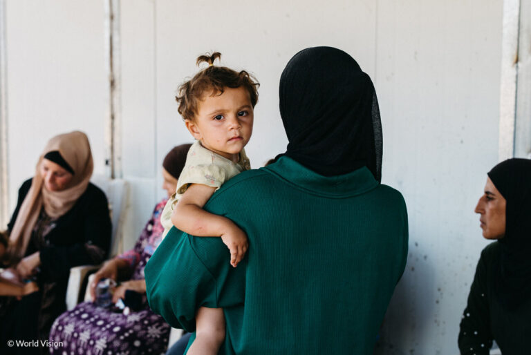 Mujer con un niño en brazos en un entorno de crisis humanitaria