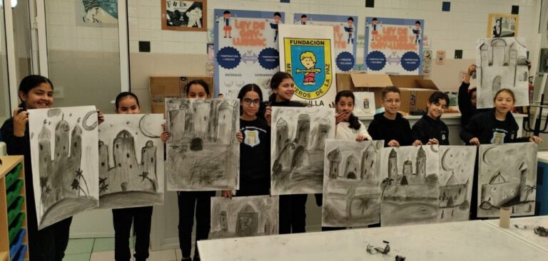 Niños sosteniendo dibujos en carboncillo en un taller de arte