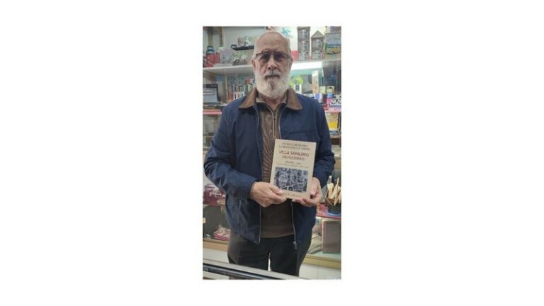 Francisco Peinado sosteniendo su libro sobre Villa Sanjurjo en un local.