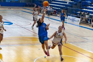 Jugadora lanzando el balón durante un partido de baloncesto femenino