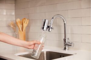 Grifo de cocina filtrando agua en un recipiente de vidrio