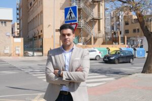 Hombre de pie en una calle con señal de peatones en Melilla.