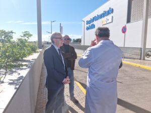 Tres hombres conversando frente al Hospital Universitario de Melilla.