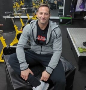 Javi Leiva sentado en un gimnasio, sonriendo y listo para entrenar.