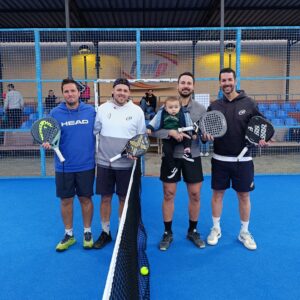 Cuatro jugadores de pádel sosteniendo raquetas junto a un bebé